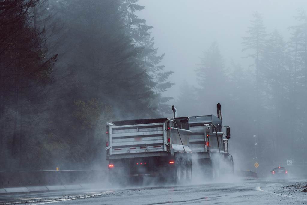 Dump trucks driving through rain and road spray